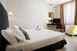 sypialnia z dużym łóżkiem z białą pościelą i poduszkami w obiekcie Hotel Palazzo Cavalieri w Syrakuzach