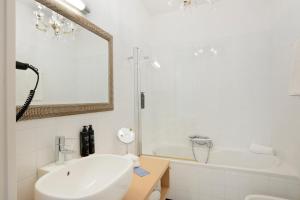 a white bathroom with a sink and a bath tub at Hotel Palazzo Cavalieri in Syracuse