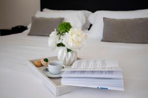 a tray with a vase of flowers and a book on a bed at Hotel Palazzo Cavalieri in Syracuse