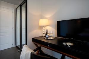 a room with a television and a table with wine glasses at Hotel Palazzo Cavalieri in Syracuse