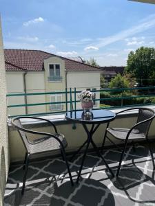 a patio table with two chairs and a vase of flowers on a balcony at Modernes Apartment in Oldenburg in Oldenburg