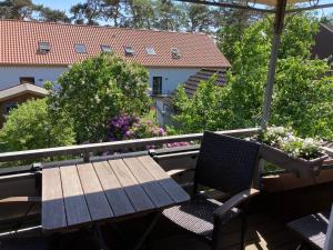 ein Holztisch und Stühle auf einem Balkon mit Blumen in der Unterkunft Ferienwohnung Heideweg in Schneverdingen