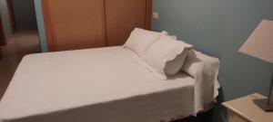 a bed with white sheets and pillows in a room at playa portonovo in Portonovo
