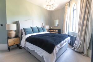 a bedroom with a large bed with blue pillows at South Lodge, St Osyth Priory in Saint Osyth