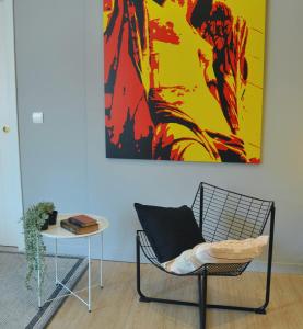una sedia e un tavolo in una stanza con un dipinto di La Casa Verde - Ruzafa a Valencia
