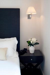 a vase of flowers on a table next to a bed at Hotel Palazzo Cavalieri in Syracuse