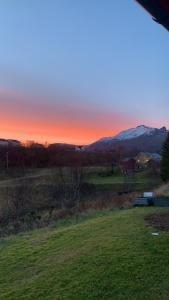 um pôr-do-sol sobre um campo com um banco num campo em Myklebostad em Steigen