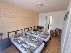 two beds in a room with wooden walls at Elch Zimmer Wilderness Life in Arvidsjaur