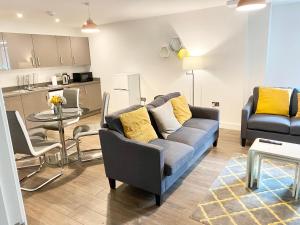 ein Wohnzimmer mit Couch und Tisch und eine Küche in der Unterkunft Queens House Apartments Coventry in Coventry