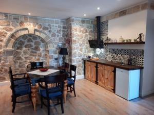 a kitchen with a table and a stone wall at Rahoni Park & Suites in Dhërmi