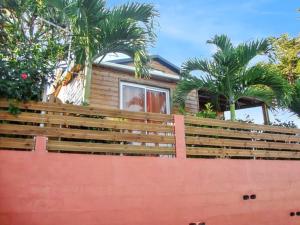 una casa con palmeras detrás de una valla de madera en Maison de 2 chambres avec vue sur la mer jardin clos et wifi a Saint Paul a 7 km de la plage en Saint-Paul