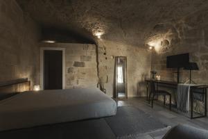 a bedroom with a bed and a desk in a room at Aque cave in Matera