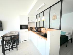 cocina con armarios blancos, escritorio y cama en Ravissant T1 au bord de l'eau Juan Les Pins, en Antibes 2 fotos más
