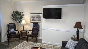 a living room with two chairs and a flat screen tv at The Riverside Inn in Saint Anthony