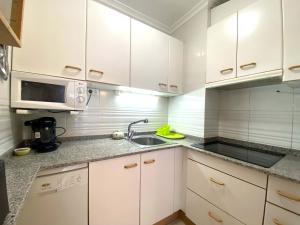 Una cocina con gabinetes blancos y un fregadero. en Cambrils PORT 11003, en Cambrils
