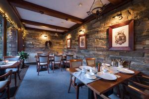 um restaurante com mesas e cadeiras de madeira e uma parede de pedra em Vila GRAND em Vysoké Tatry