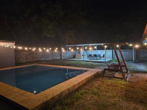 a pool with a swing and a house at night at Casa Naboo in Santa Cruz
