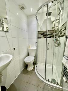 uma casa de banho com um WC e uma cabina de duche em vidro. em Cromwell Apartments em Londres