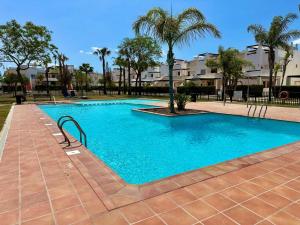 a large blue swimming pool with palm trees and buildings at VILLA IZAN in Alhama de Murcia