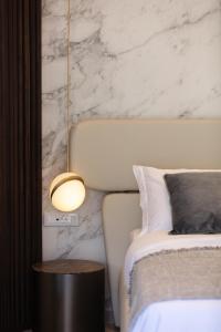 - une chambre avec un lit et un mur en marbre blanc dans l'établissement Naiades Boutique Hotel - Adults Only, à Elounda