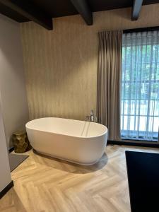 a large white tub in a bathroom with a window at Hotel Restaurant Het Witte Paard in Delden