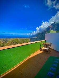 een tafel en stoelen op een balkon met uitzicht op de oceaan bij ApKanariooo in Frontera