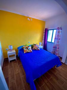 1 dormitorio con cama azul y pared amarilla en ApKanariooo, en La Frontera