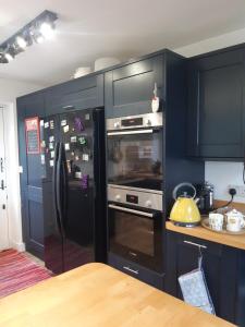 a kitchen with black cabinets and a refrigerator at Marlow in Swanage