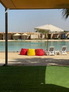 a group of colorful pillows sitting next to a pool at Deluxe Cabana with Vagaza signature in Hacienda Bay North Coast in El Alamein
