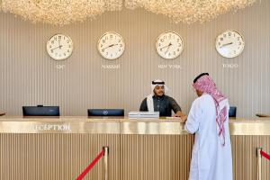 un homme et une femme debout au comptoir avec horloges dans l'établissement Paradise Nice Hotel Jeddah, à Djeddah