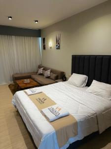 um quarto de hotel com uma cama grande e um sofá em Deluxe Cabana with Vagaza signature in Hacienda Bay North Coast em El Alamein