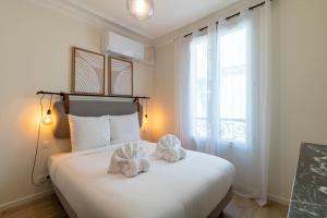 Un dormitorio con una gran cama blanca con toallas. en B3#Two Bedrooms#Champs Elysées#Arc de Triomphe#AC, en París