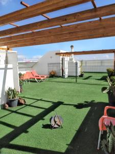 une terrasse avec de la pelouse verte et une pergola en bois. dans l'établissement One bedroom apartement at Arinaga 500 m away from the beach with terrace and wifi, à Arinaga