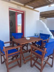 a dining room with blue chairs and a wooden table at Studios Venetsanos in Koufonisia