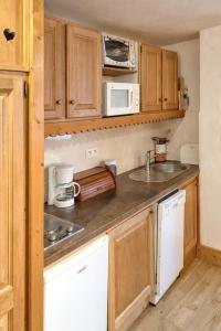 a small kitchen with wooden cabinets and a sink at Studio a La Plagne Tarentaise a 300 m des pistes avec balcon amenage et wifi in La Plagne Tarentaise