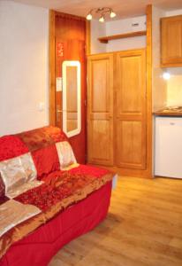 a bedroom with a red bed and a kitchen at Studio a La Plagne Tarentaise a 300 m des pistes avec balcon amenage et wifi in La Plagne Tarentaise