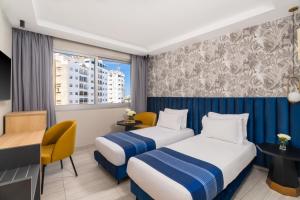 a hotel room with two beds and a desk at Kenzi Solazur in Tangier
