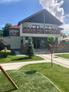 a large house with a porch and a lawn at Pensiunea Magic in Băile Govora