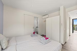 a white bedroom with two beds with flowers on them at Malvales Resort in Willemstad