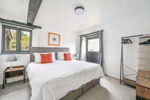 a bedroom with a large bed with white sheets and orange pillows at Goonwinnow Farm Cottages in Newquay