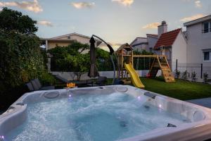 a hot tub in a backyard with a playground at Apartments Solmar in Podstrana