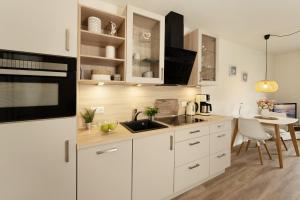 a kitchen with white cabinets and a dining table at Pier 67 Ostseeglück Neustadt in Neustadt in Holstein