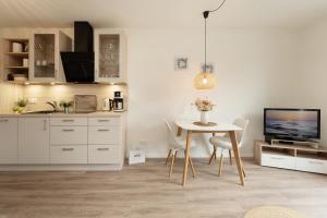 a white kitchen with a table and a tv at Pier 67 Ostseeglück Neustadt in Neustadt in Holstein