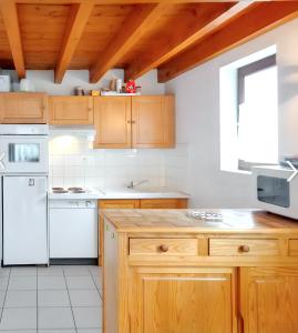 una cocina con electrodomésticos blancos y armarios de madera en Maison de 3 chambres avec jardin clos a Aragnouet a 6 km des pistes, en Aragnouet