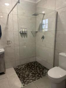 uma casa de banho com uma cabina de duche em vidro e um WC. em Mabalel Lodge em Nelspruit
