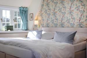 ein Bett mit zwei Kissen in einem Zimmer mit einem Fenster in der Unterkunft Hotel Seiler Hof Keitum garni in Keitum