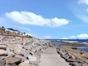 a group of people laying on the rocks on the beach at Studio with wifi at Las Palmas de Gran Canaria 1 km away from the beach in Las Palmas de Gran Canaria