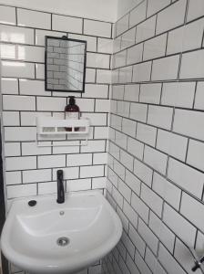 a white tiled bathroom with a sink and a mirror at D' Tanjung Homestay-Orked in Pekan