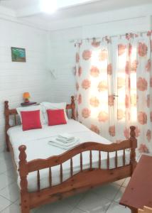 1 dormitorio con cama de madera y almohadas rojas en Villa de 3 chambres avec vue sur la mer piscine privee et jardin clos a Le Carbet a 2 km de la plage en Le Carbet