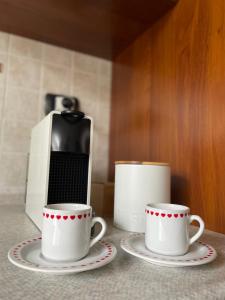 two coffee cups and a cell phone on a counter at Appartamento Villa Asio in Lignano Sabbiadoro